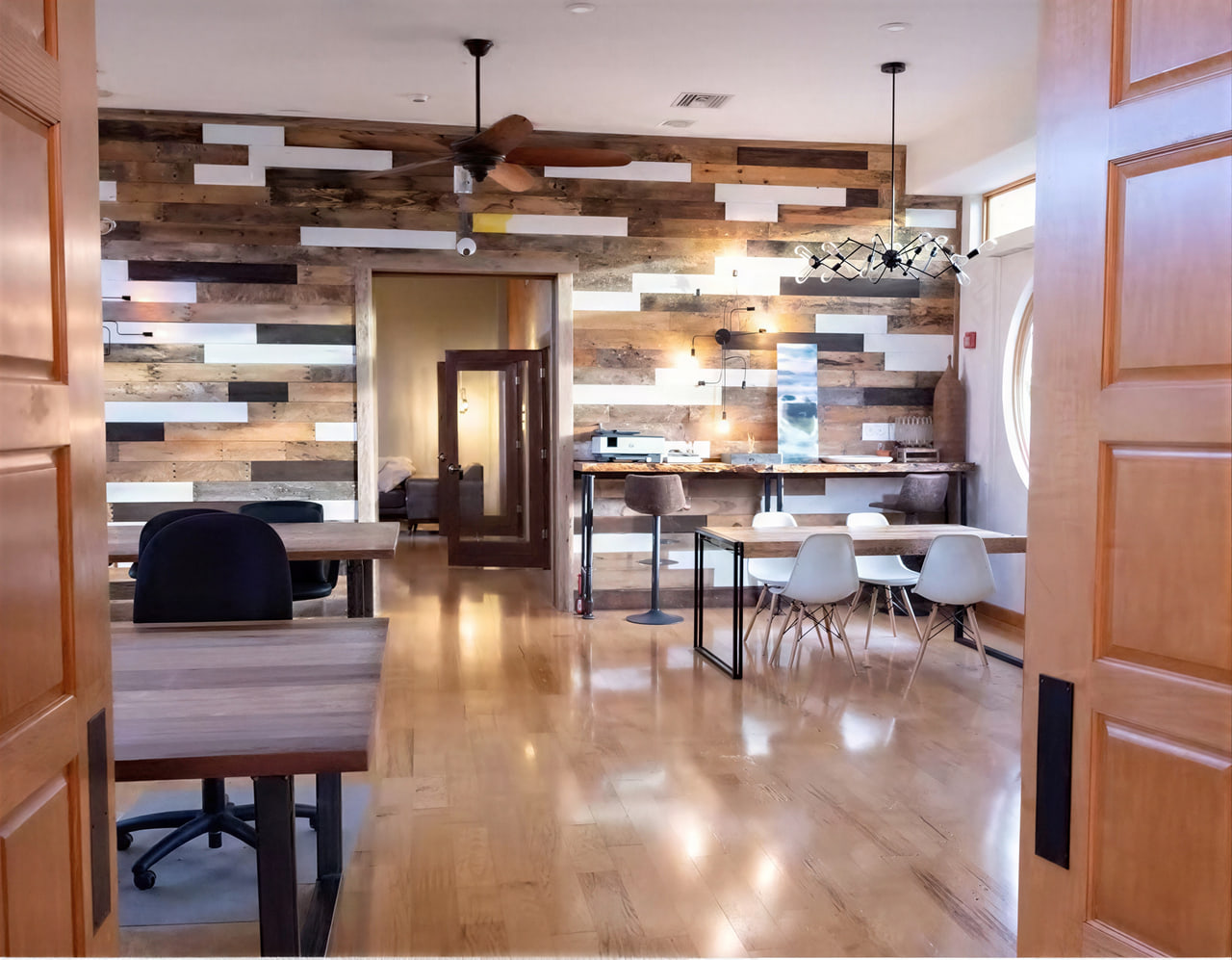 Interior of the Spring River high-school home on Pine Street, a bright room with reclaimed-wood accent walls, wood floors, a communal high table, and modern chairs.